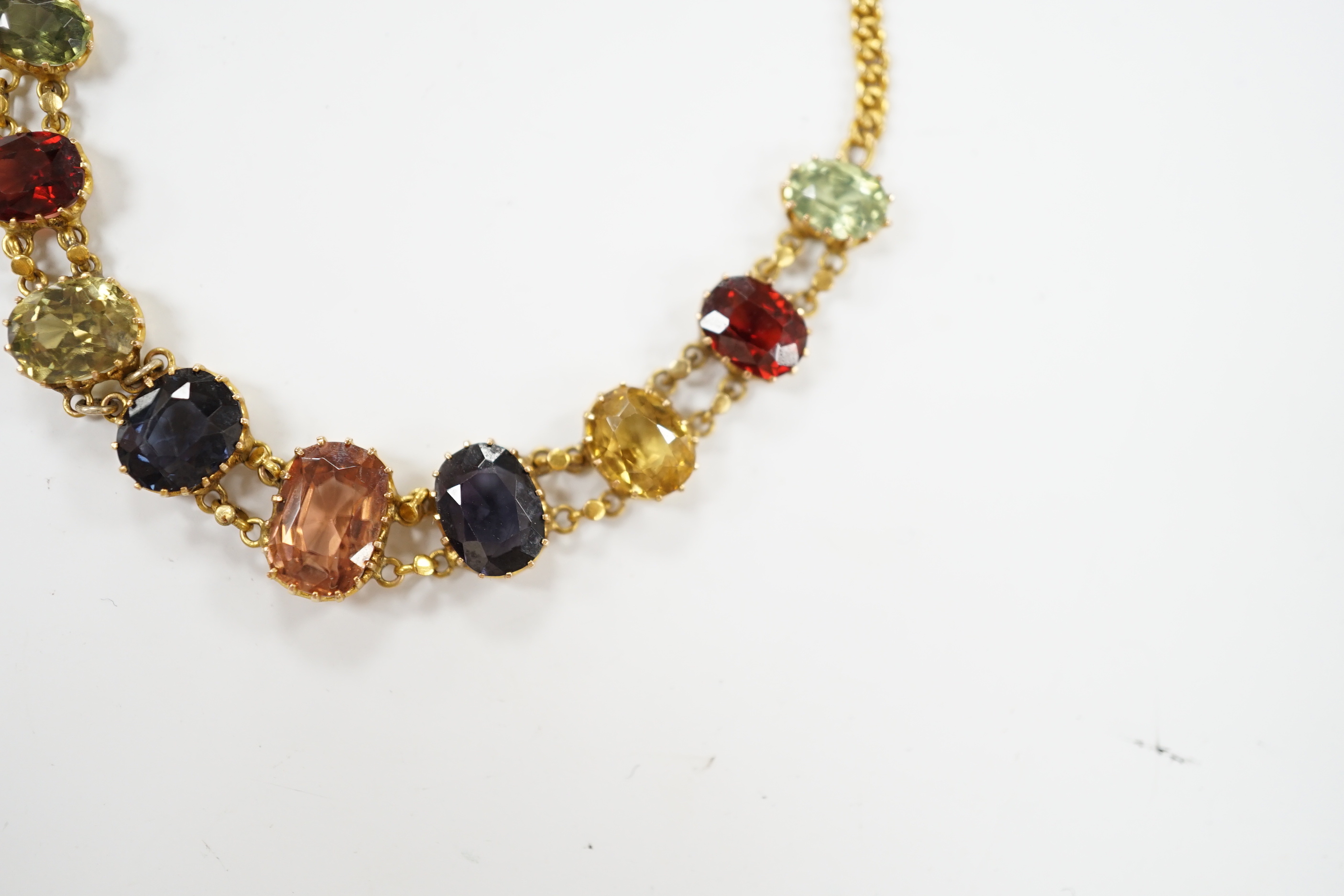 An early 20th century yellow metal and graduated multi-coloured oval cut zircon? set bracelet, 15.5cm, gross weight 7 grams.